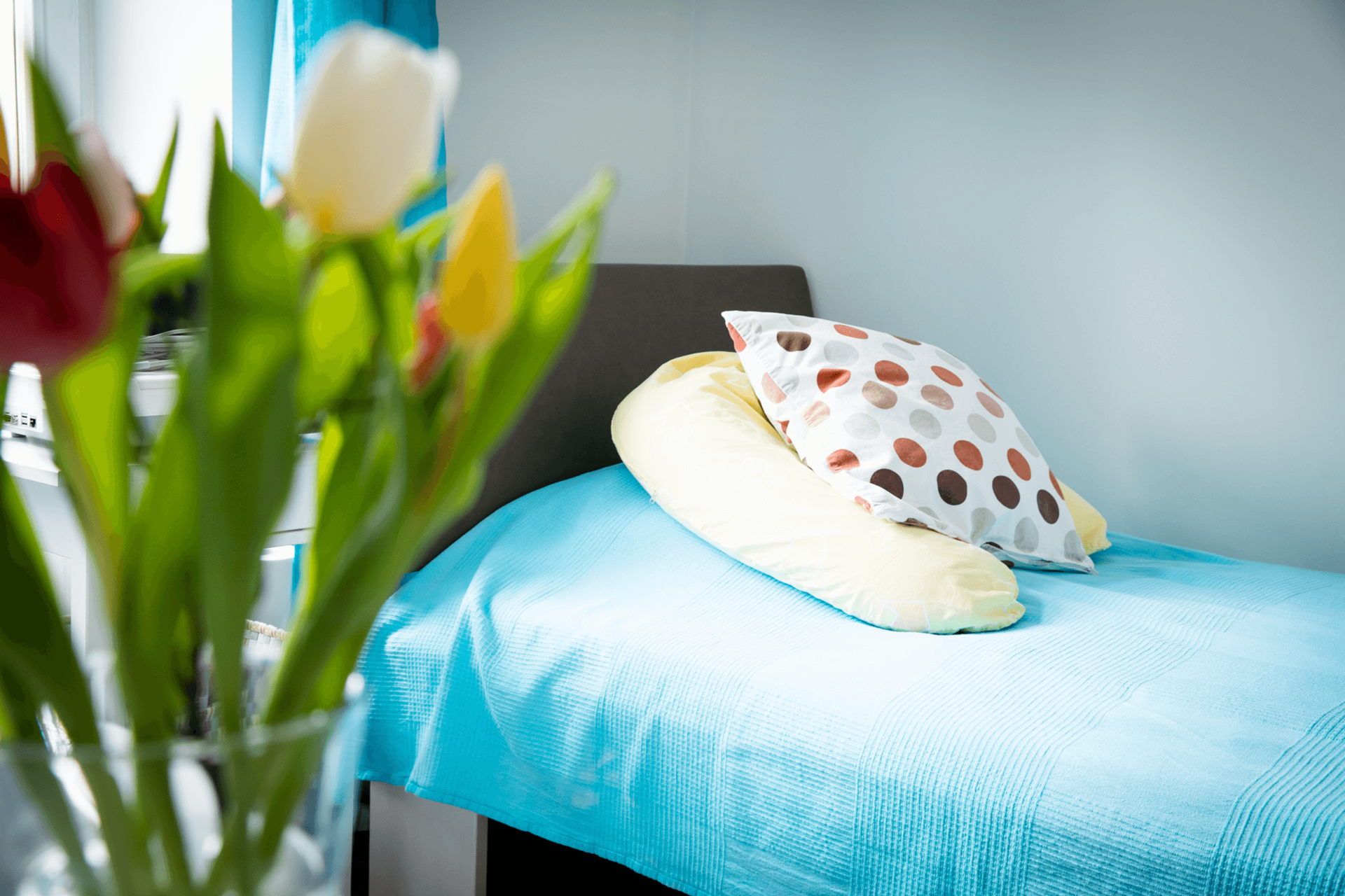 Bett mit Kissen und Blumen im Vordergrund